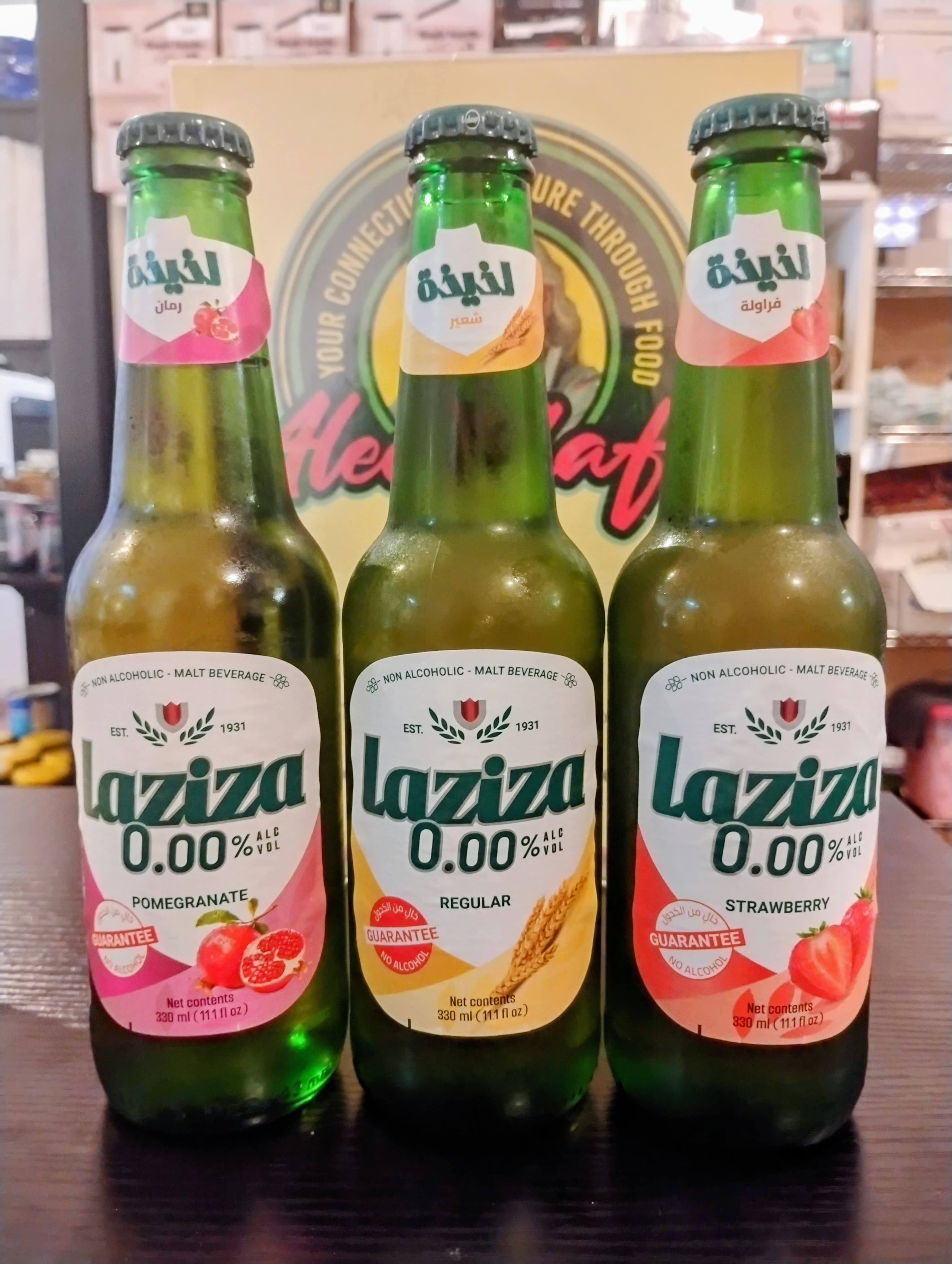 Three green bottles of Laziza non-alcoholic malt beverage: pomegranate, regular, and strawberry flavors.